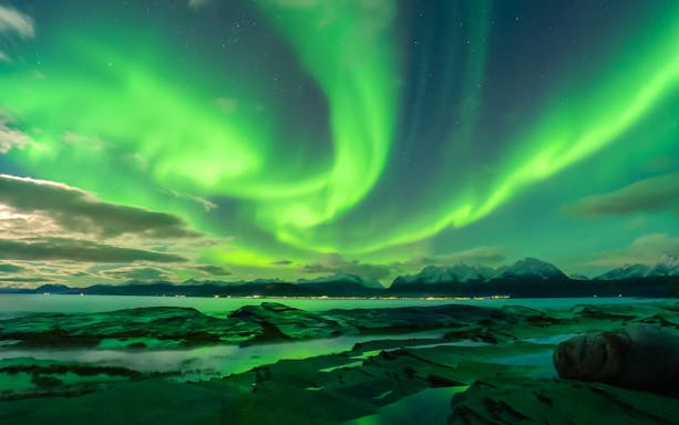 Northern Lights over Tromso fjord and mountains, Norway.