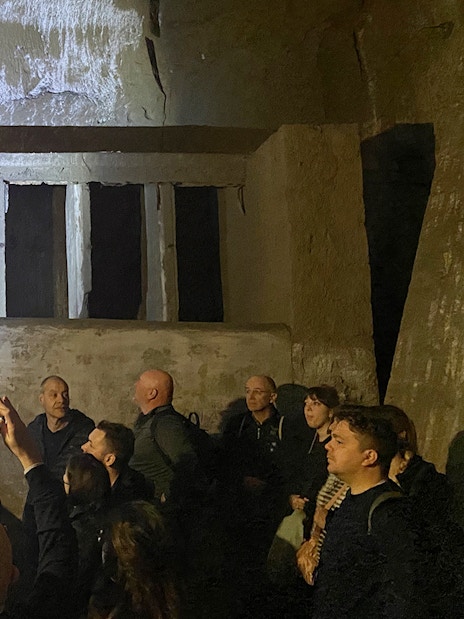 People exploring ancient walls during a guided tour in Naples underground.
