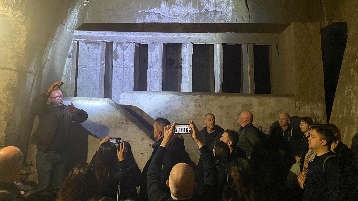 People exploring ancient walls on Naples Underground Guided Tour.
