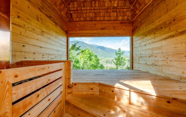 Wooden sauna interior with mountain view at QC Terme Bagni Nuovi di Bormio.