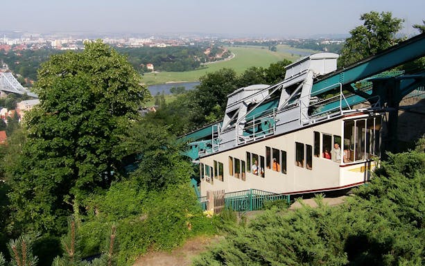 Dresden cable car ascending with cityscape and river view in background.