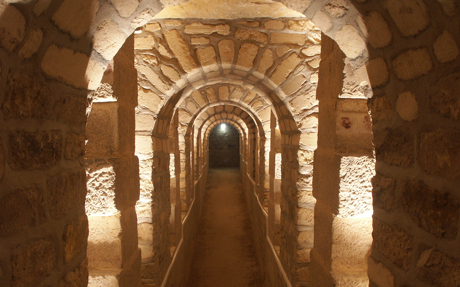 Stone archway in the Paris Catacombs, illuminated passageway.