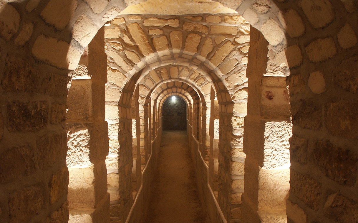 Stone archway in the Paris Catacombs, illuminated passageway.