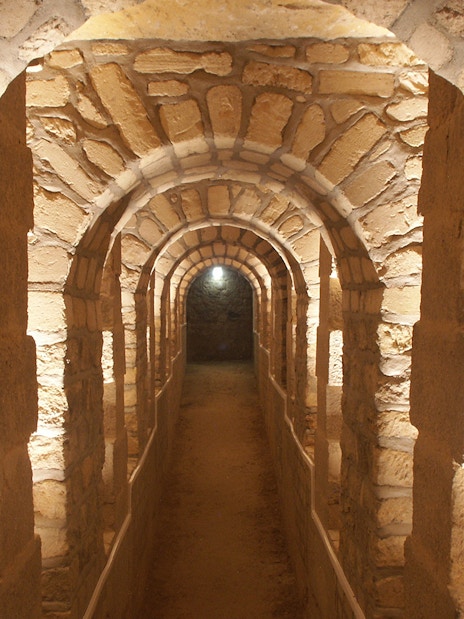 Stone archway in the Paris Catacombs, illuminated passageway.