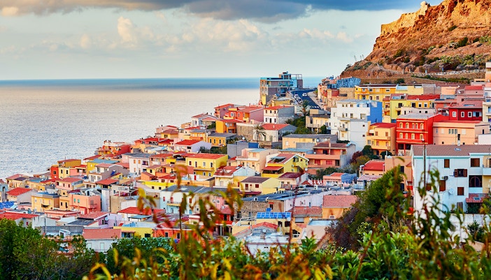 Sardinia cityscape at sunset with historic buildings and coastline.