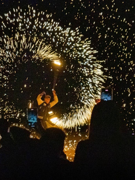 Fire performer at night show in Agafay Desert, Marrakesh with sparks flying.
