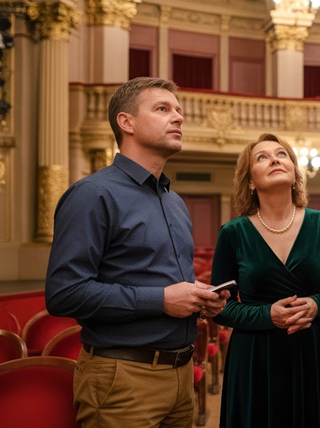 Tour guide with guests inside the Hungarian State Opera, admiring the ornate interior.