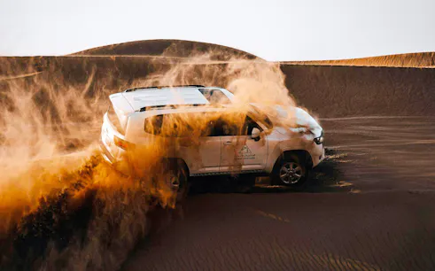 SUV driving through sand dunes during Dubai desert safari.