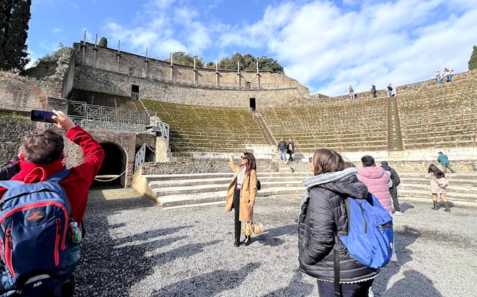 Tourists exploring the ancient amphitheater in Herculaneum, Pompeii.