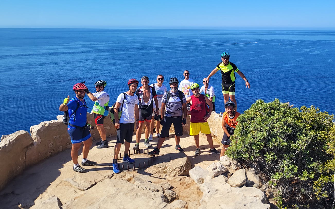 Group of bikers posing on a coastal cliff with ocean view.