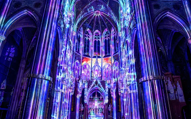 Vibrant light display inside Votivkirche, Vienna, showcasing colorful illuminated arches.