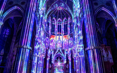 Vibrant light display inside Votivkirche, Vienna, showcasing colorful illuminated arches.