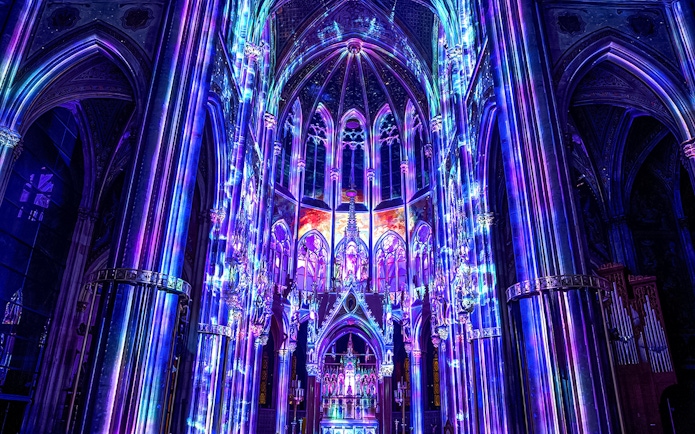 Vibrant light display inside Votivkirche, Vienna, showcasing colorful illuminated arches.