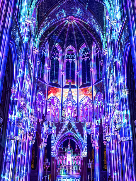 Vibrant light display inside Votivkirche, Vienna, showcasing colorful illuminated arches.