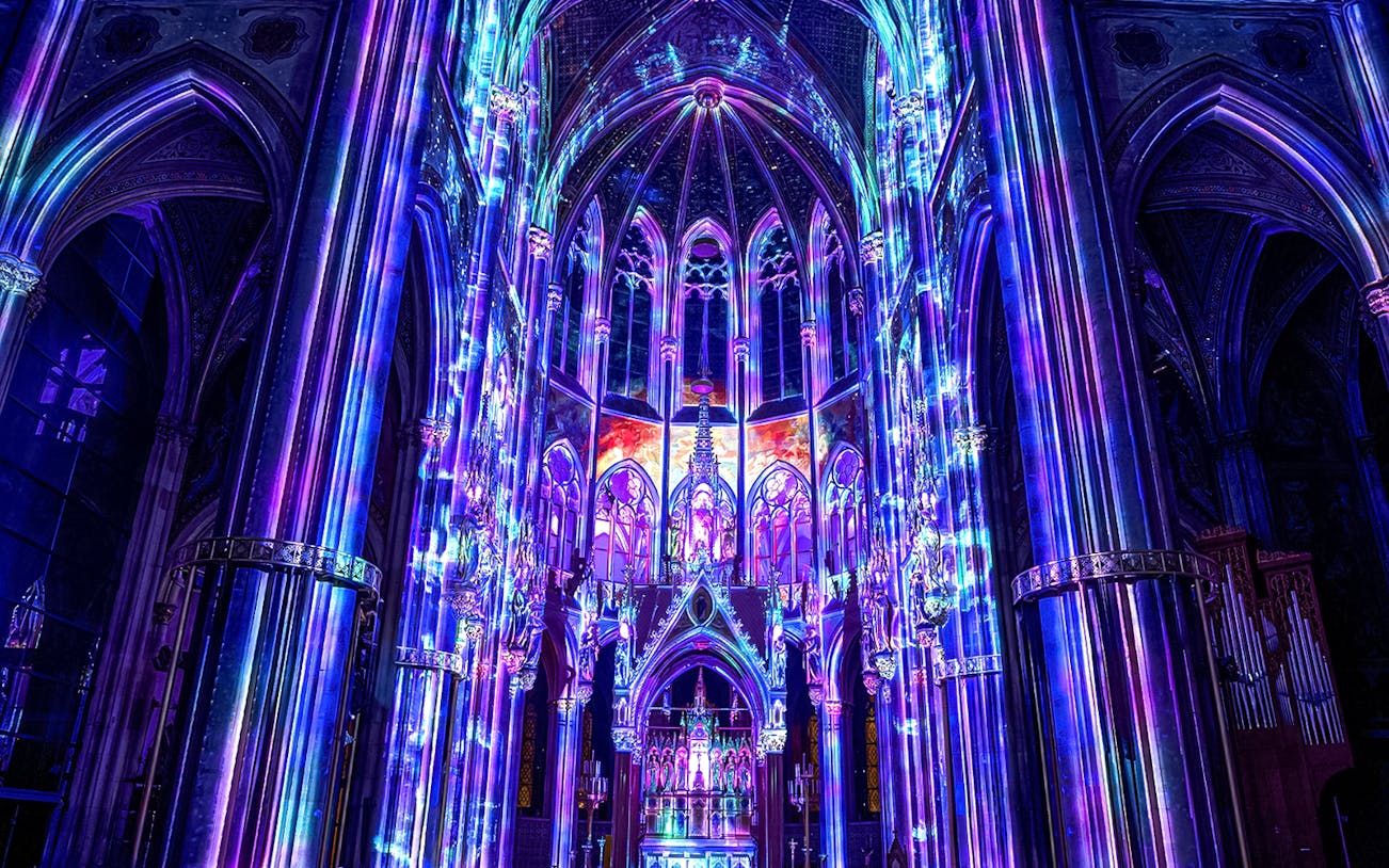 Vibrant light display inside Votivkirche, Vienna, showcasing colorful illuminated arches.