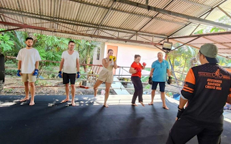 Muay Thai class in Bangkok's Green Lung with participants practicing under a tin roof.
