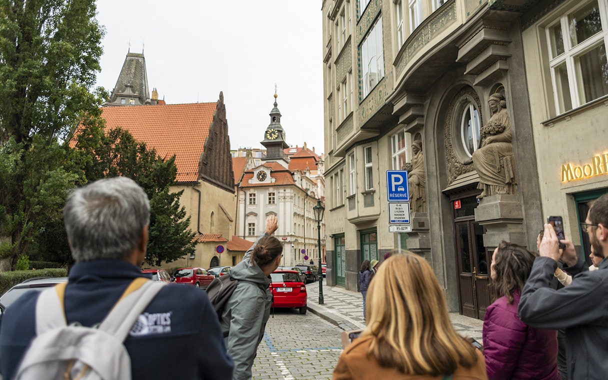 Guests with tour guide exploring Jewish Quarters in Prague, viewing historic architecture.