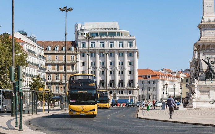 Lisbon hop-on hop-off bus near Altis Avenida Hotel and monument.