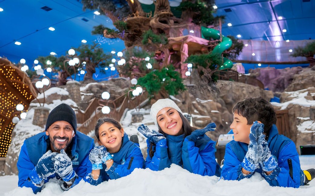 Family enjoying snow activities at Snow Abu Dhabi indoor park.