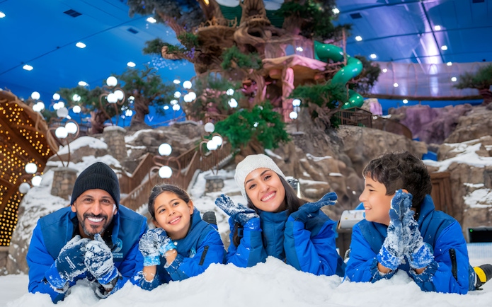 Family enjoying snow activities at Snow Abu Dhabi indoor park.
