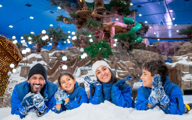 Family enjoying snow activities at Snow Abu Dhabi indoor park.