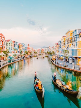 Gondolas on a canal surrounded by colorful buildings at VinWonders Phu Quoc Theme Park.