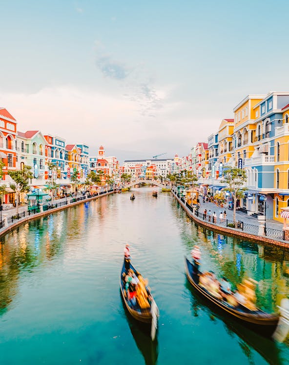 Gondolas on a canal surrounded by colorful buildings at VinWonders Phu Quoc Theme Park.
