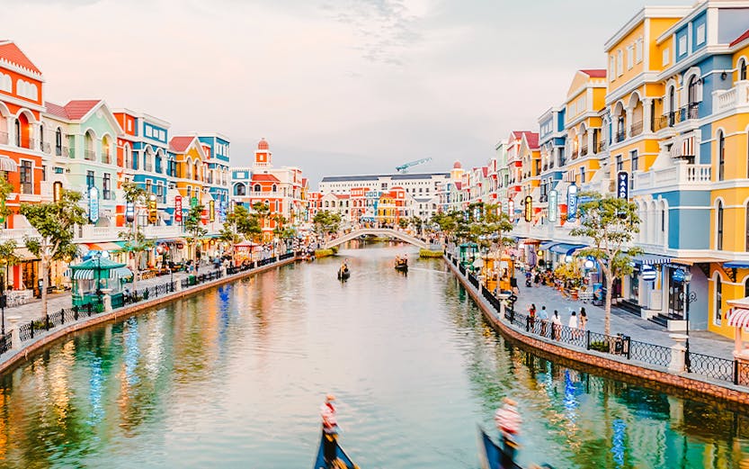 Gondolas on a canal surrounded by colorful buildings at VinWonders Phu Quoc Theme Park.