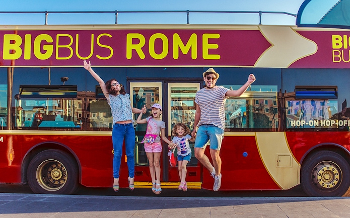 Family jumping in front of Big Bus Rome, excited for city tour.