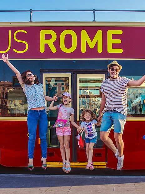 Family jumping in front of Big Bus Rome, excited for city tour.