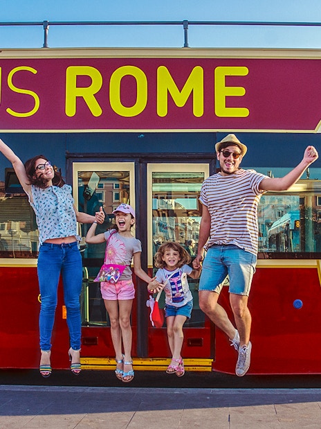 Family jumping in front of Big Bus Rome, excited for city tour.