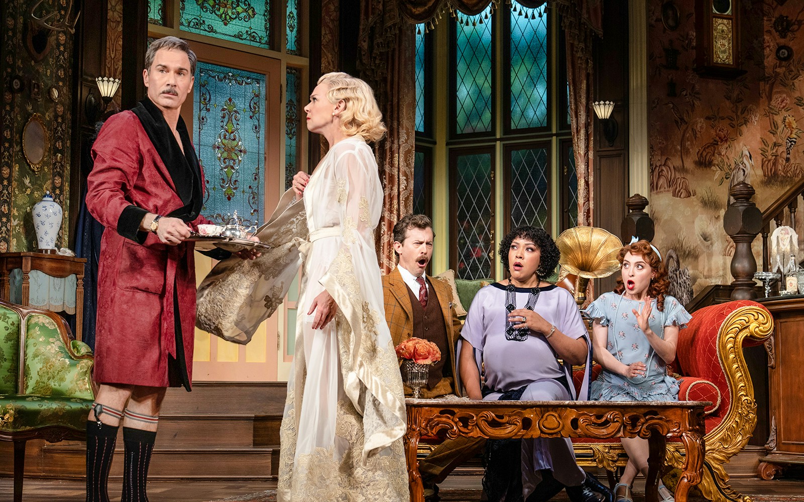 Guests in vintage attire react in surprise inside an ornate room at The Cottage.