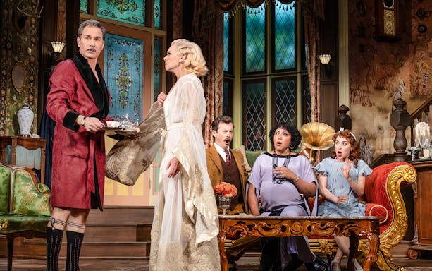 Guests in vintage attire react in surprise inside an ornate room at The Cottage.