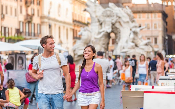 Couple walking near the Fountain of the Four Rivers in Rome.