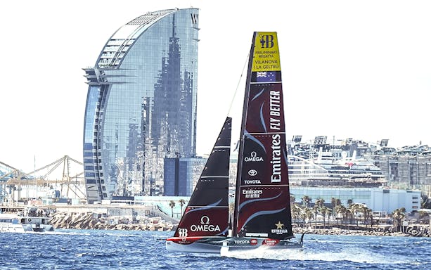 Sailing yacht in Barcelona's harbor with iconic W Hotel in the background.