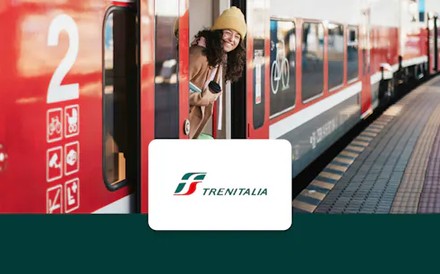Girl smiling from Trenitalia train at station platform.