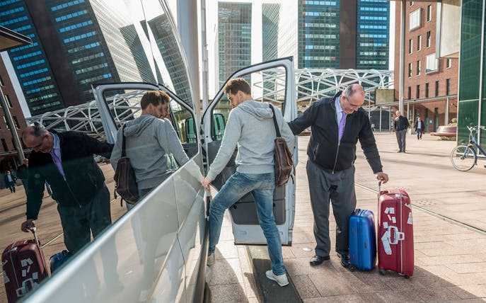 Passengers boarding a shuttle with luggage at an airport transfer location.
