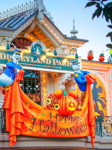 Disneyland Paris entrance with Halloween decorations and ghost figures.