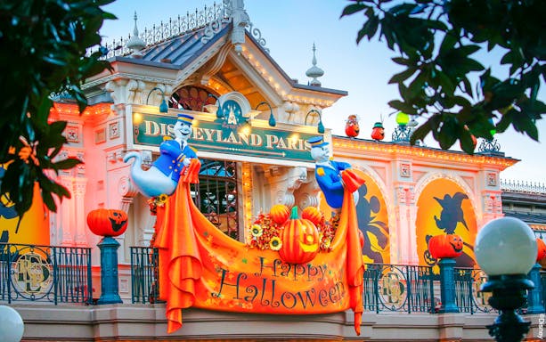 Disneyland Paris entrance with Halloween decorations and ghost figures.