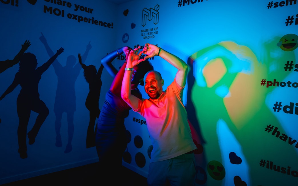 Visitor interacting with colorful light exhibit at Museum of Illusions, Madrid.