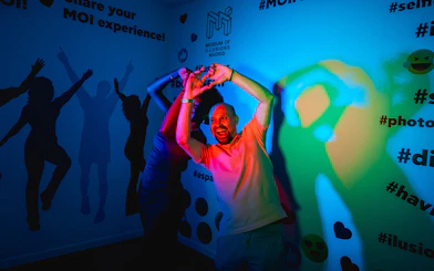 Visitor interacting with colorful light exhibit at Museum of Illusions, Madrid.
