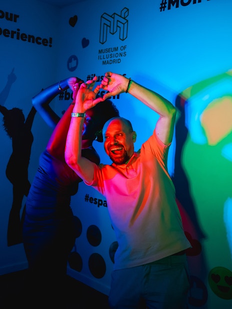 Visitor interacting with colorful light exhibit at Museum of Illusions, Madrid.