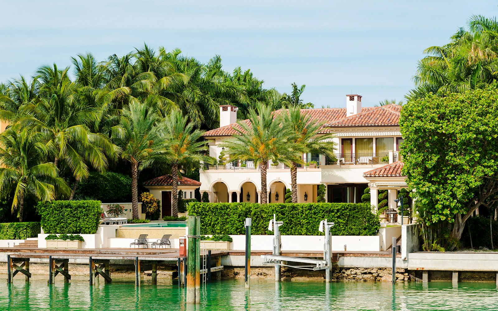 Luxurious mansion on Star Island with palm trees and waterfront view in Miami.