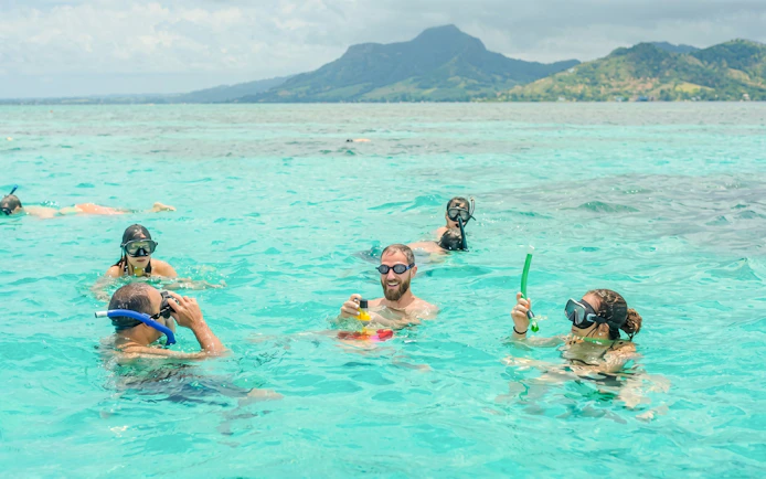 Snorkelers enjoying clear waters with a mountain view in Mauritius.