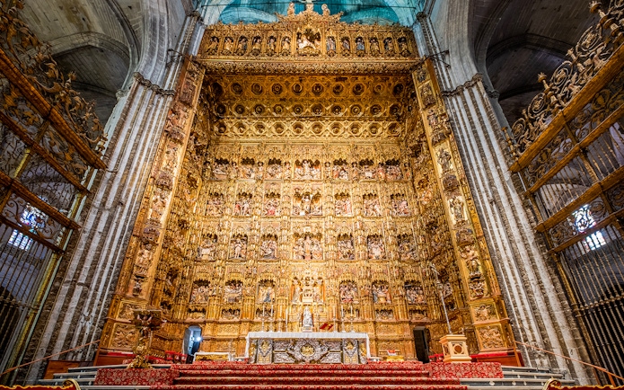 Altar of Seville Cathedral with intricate gold detailing on a guided tour.