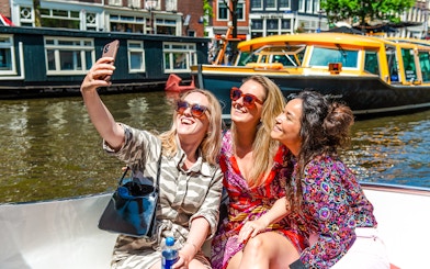 Tourists taking a selfie on a canal cruise during Sail Amsterdam.