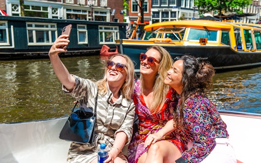 Tourists taking a selfie on a canal cruise during Sail Amsterdam.