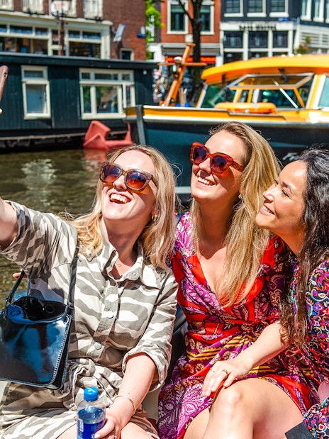 Tourists taking a selfie on a canal cruise during Sail Amsterdam.