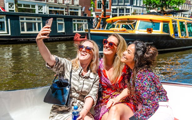 Tourists taking a selfie on a canal cruise during Sail Amsterdam.