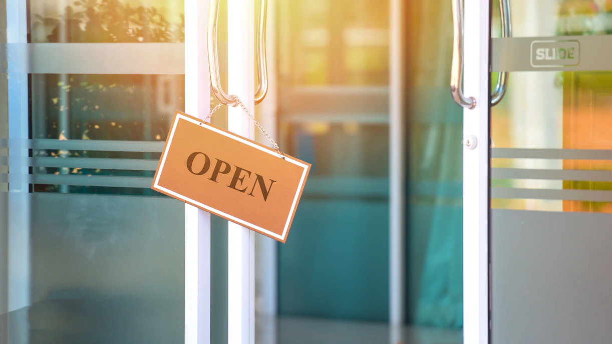 Open sign hanging on a glass door during business hours.